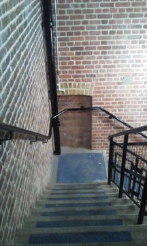 Stairs descending with brick walls to left and ahead