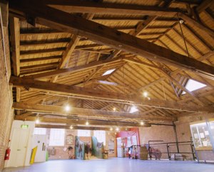 Pine-coloured timber pitched roof above large empty gallery with brick walls