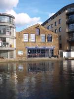 The museum is seen from the canal basin with blue sky behind and reflection on the water