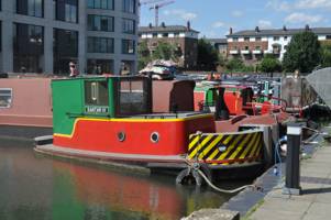 Red green and yellow painted tug moored on wharf