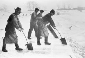 Men cut ice with saws from a frozen lake