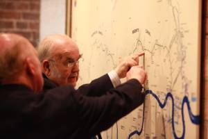 Two adult visitors scrutinise a large detailed map on the wall