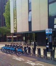 Cycles in racks for hire, tall building behind