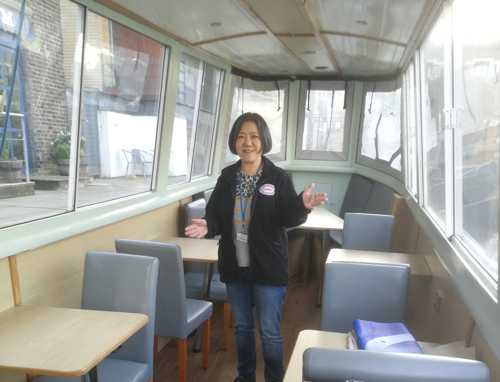 A volunteer guide aboard. Tables and chairs to her right and left