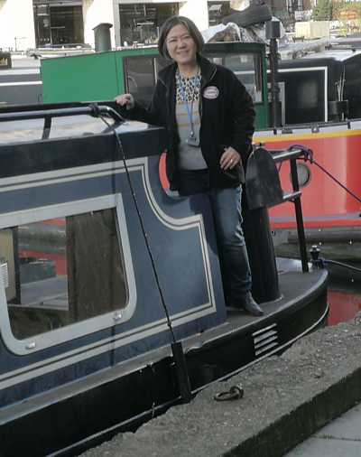 Volunteer guide stands on stern of boat, other boats in background