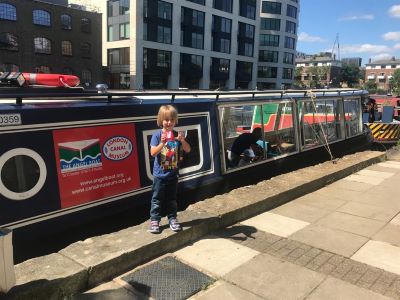 Child stands in front of boat Long Tom